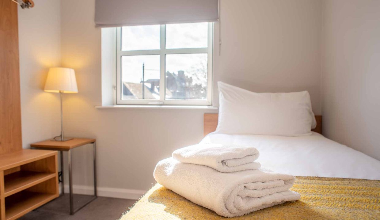 Bed and fluffy towels with wardrobe and natural light at PREMIER SUITES Reading